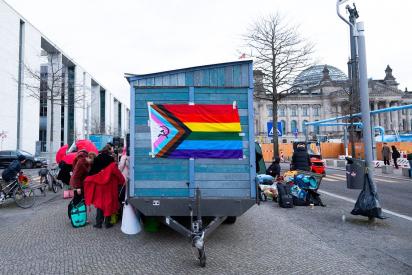 Ein Saunawagen mit Regenbogenflagge steht zwischen Paul-Löbe-Haus und Bundestag